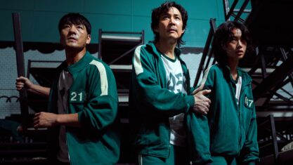 Jung-jae, Park Hae-soo, Jung Ho-yeon in Squid Game. They are sweaty and blood in their tracksuits as they face forward looking tired and concerned.